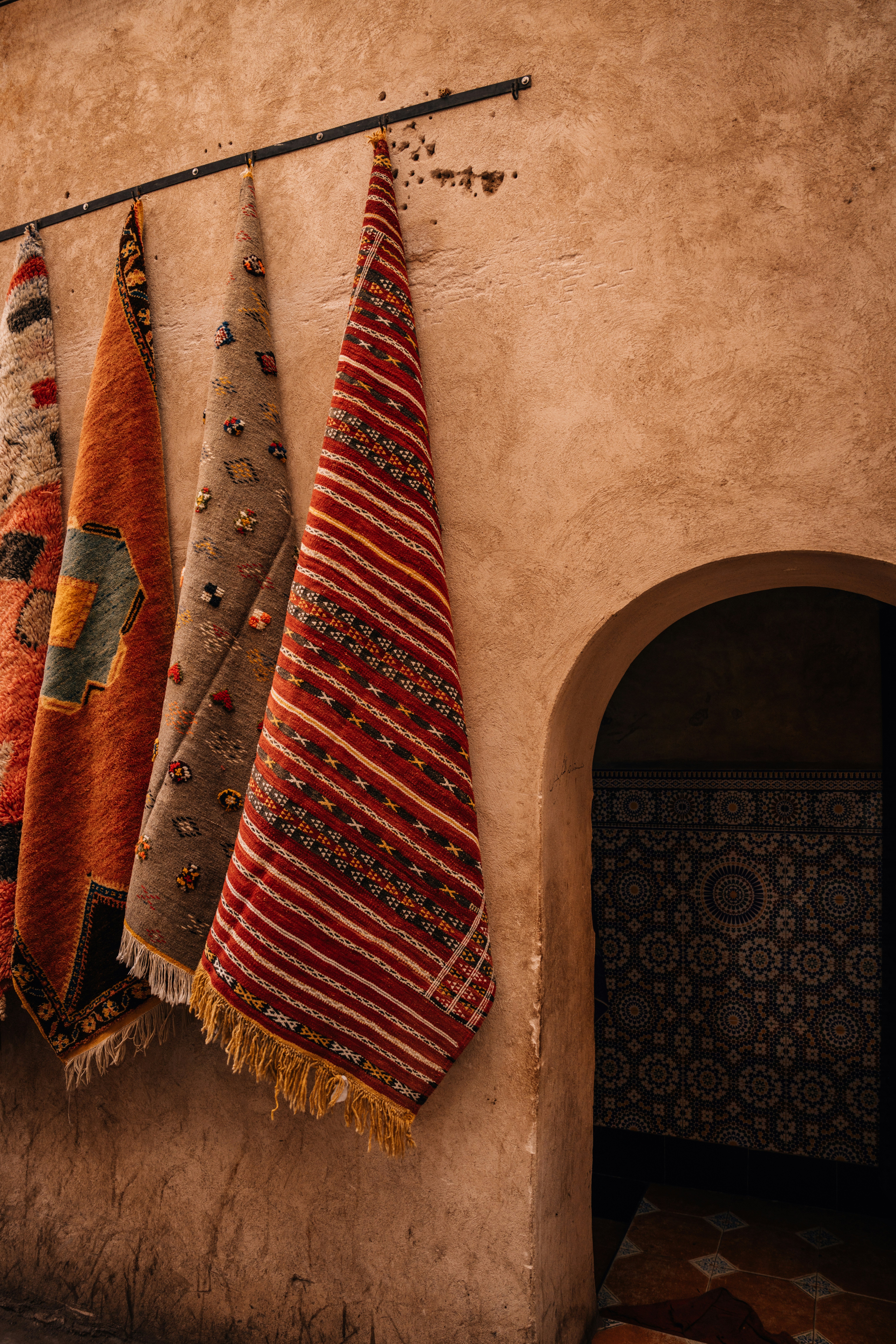 Rugs hanging against a terracotta wall with Moroccan arch, Marrakech